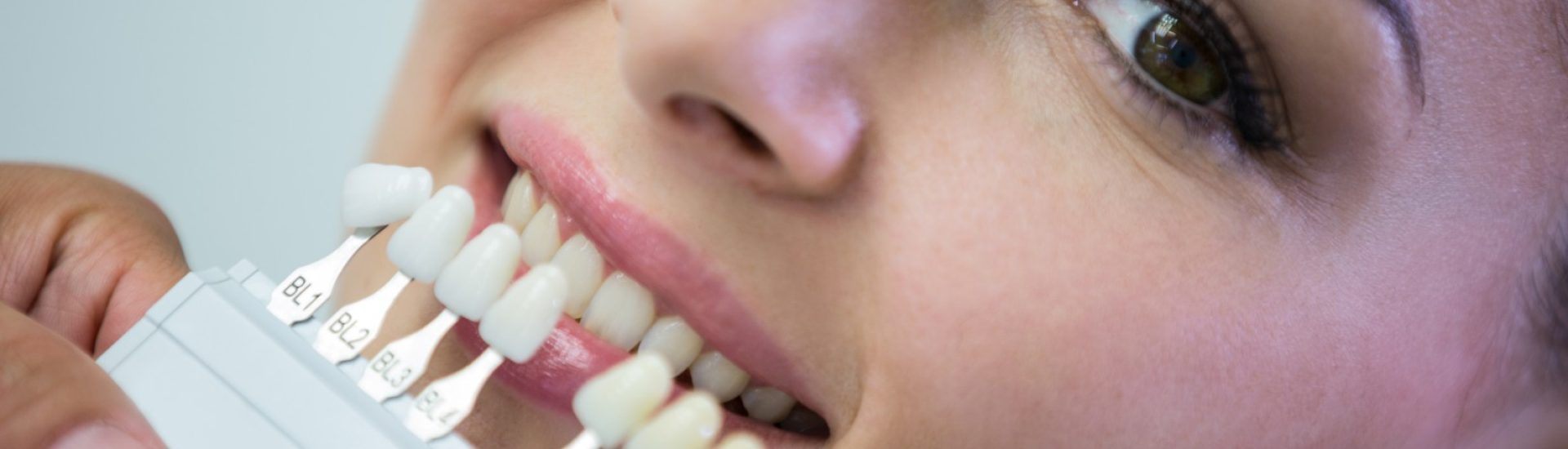 Dentist examining female patient with teeth shades at dental clinic